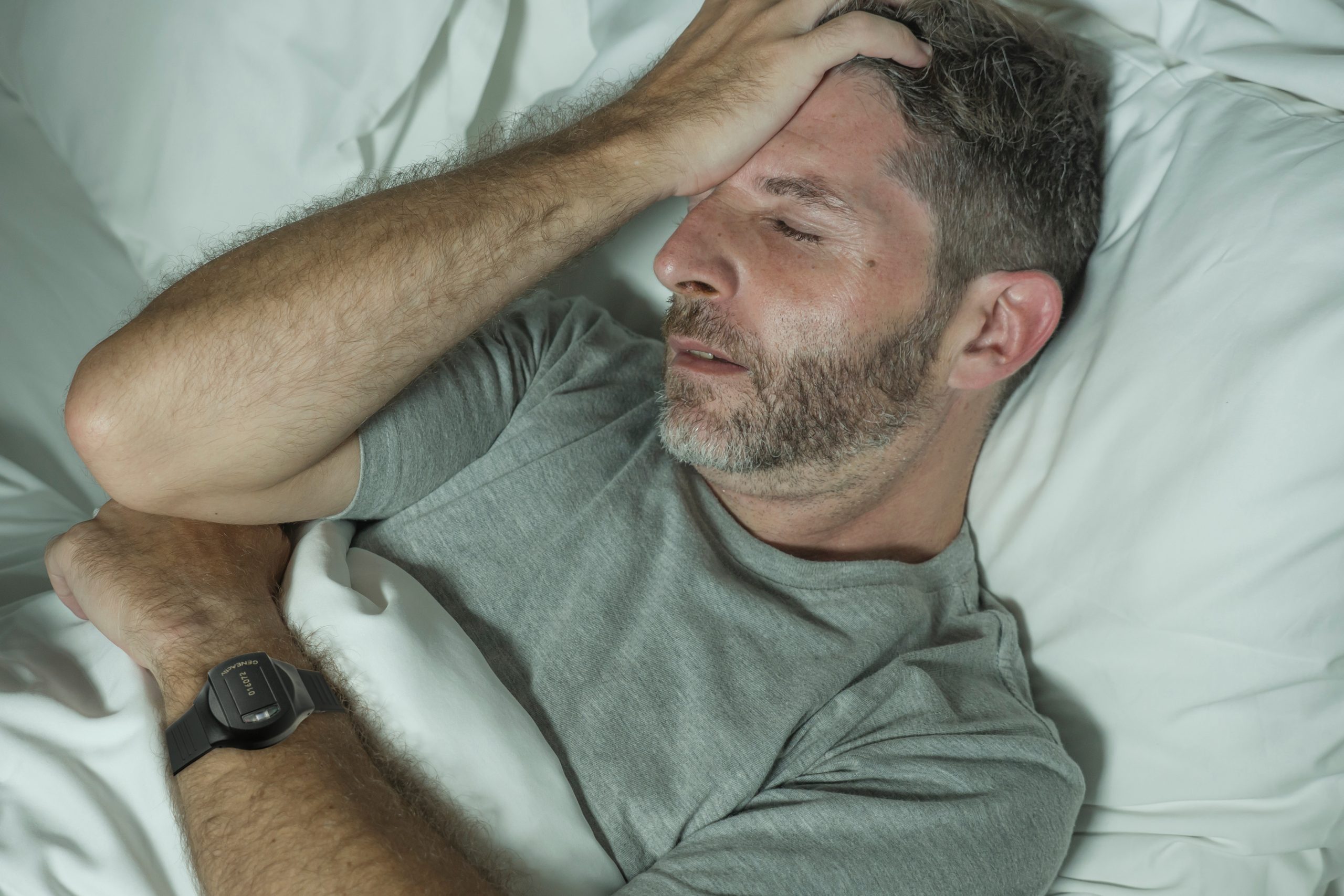 dramatic portrait of stressed and frustrated man in bed awake at